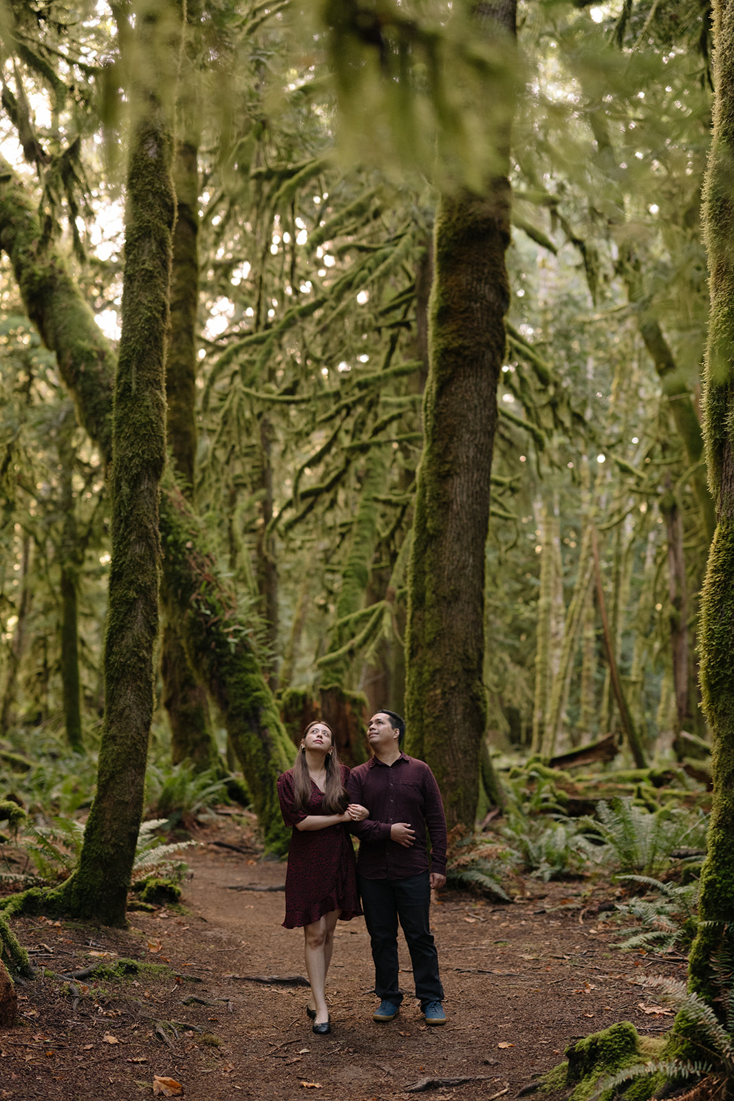 Couple walking through ancient moss-draped old growth forest at Lake Crescent, one of the best places to elope on the Washington coast, Olympic National Park