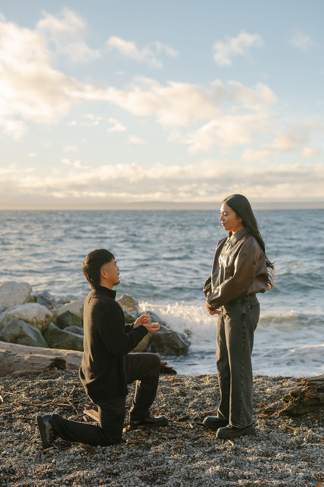 Groom-to-be gets down on one knee to propose at Pocket Beach with Puget Sound in the background