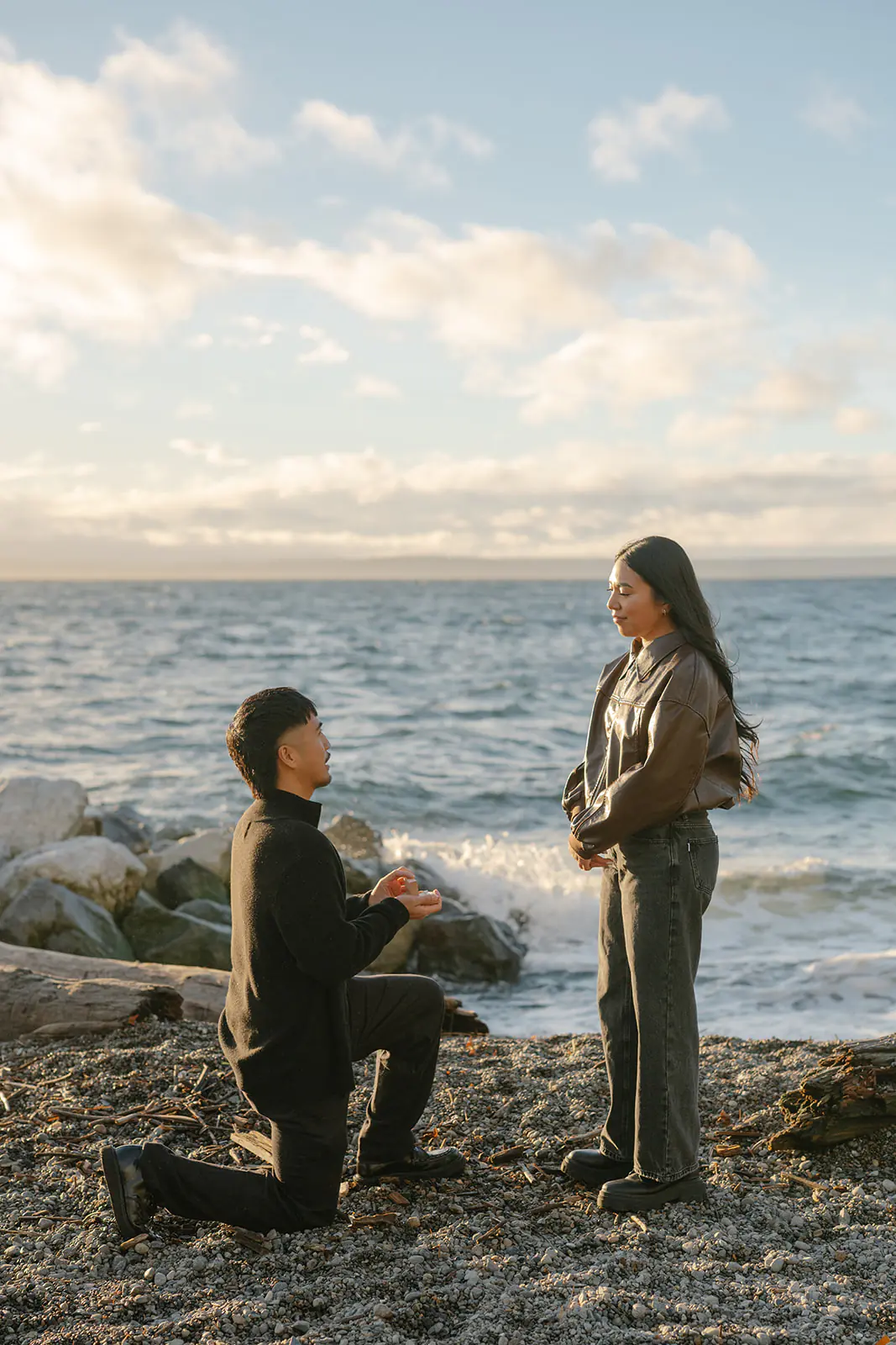 Groom-to-be gets down on one knee to propose at Pocket Beach with Puget Sound in the background