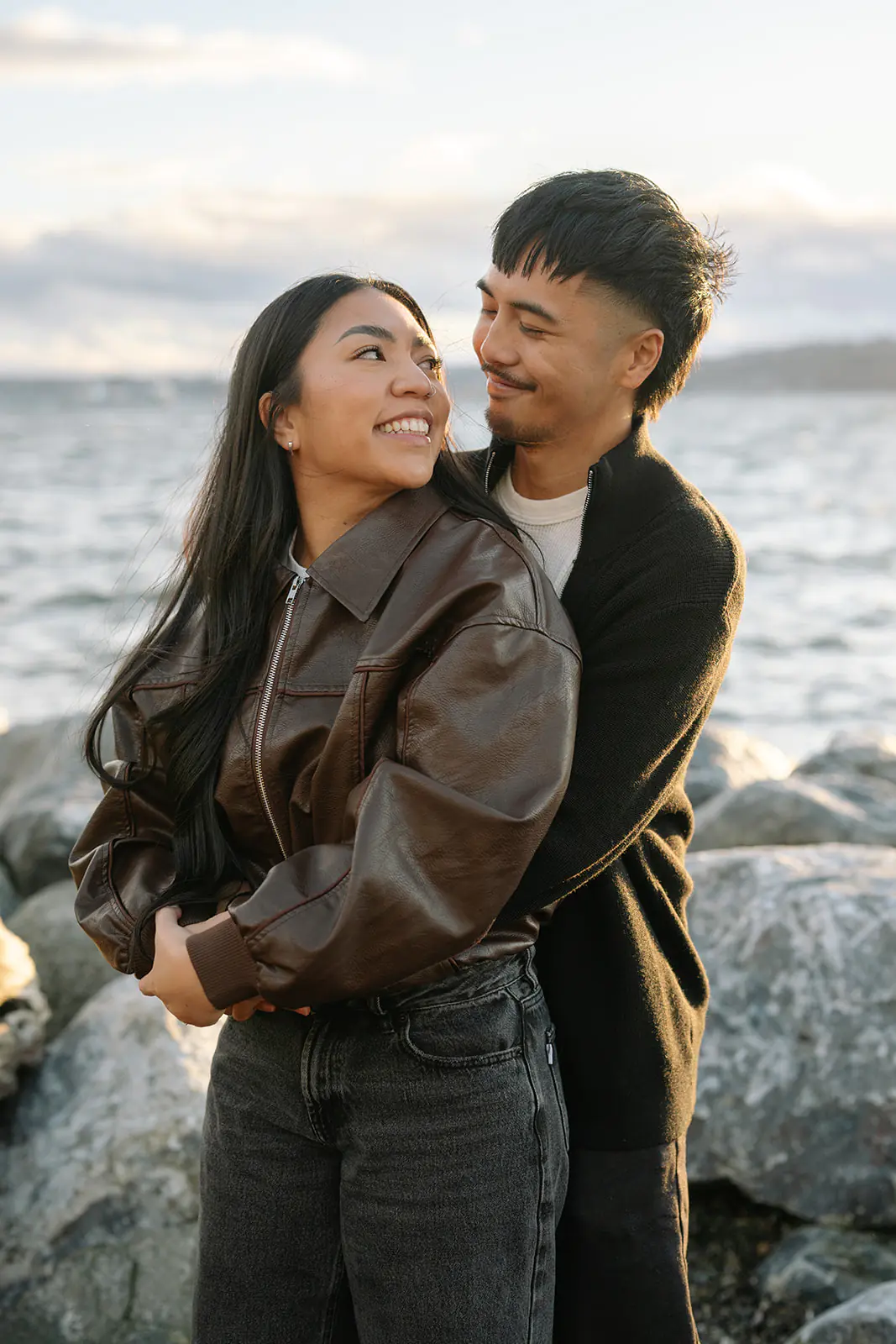 Seattle beach engagement portrait of newly engaged couple laughing on the rocky shore at Pocket Beach

