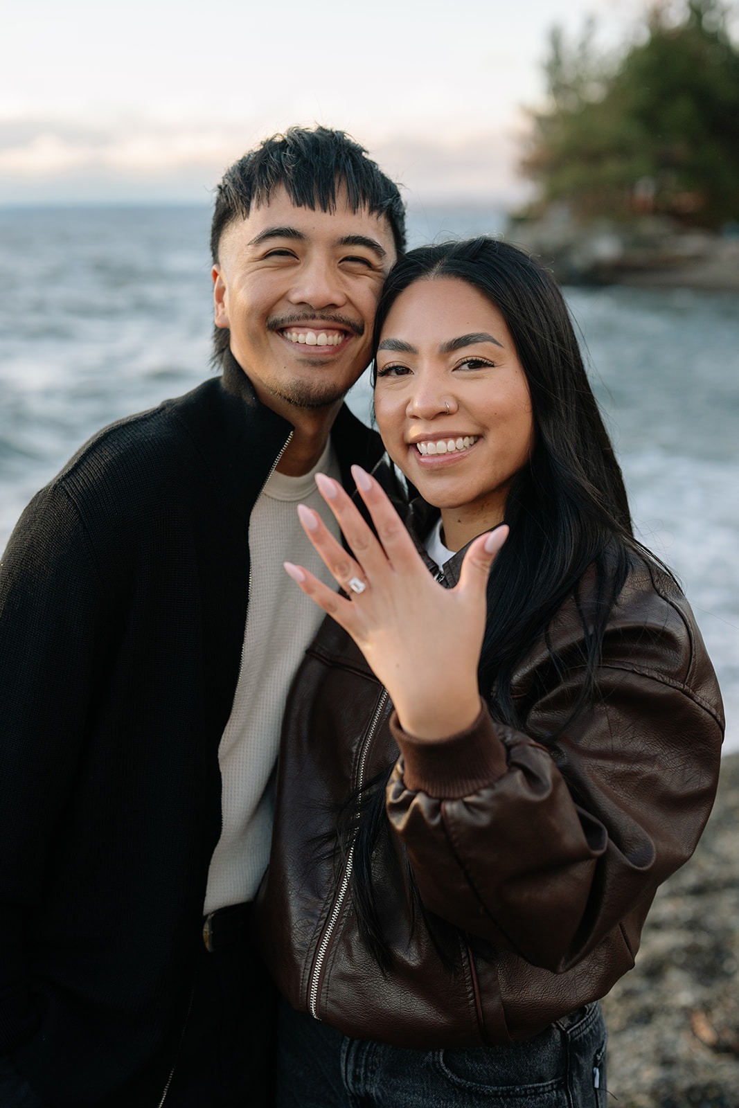 Newly engaged couple grins as she shows off her engagement ring at Pocket Beach in Seattle