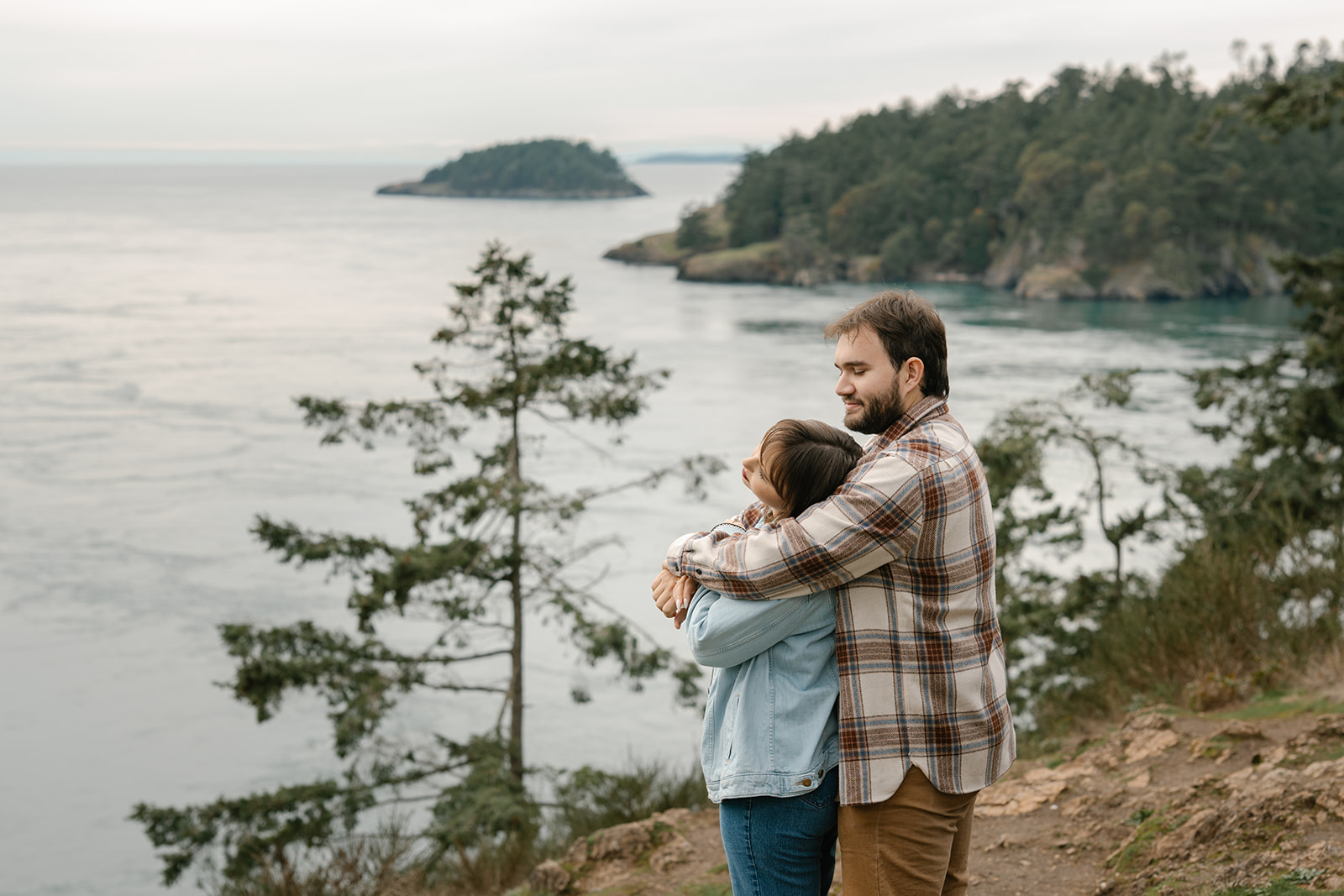 Jonathan holds Ashley close as they overlook the water at Deception Pass, sharing a quiet moment after their proposal.