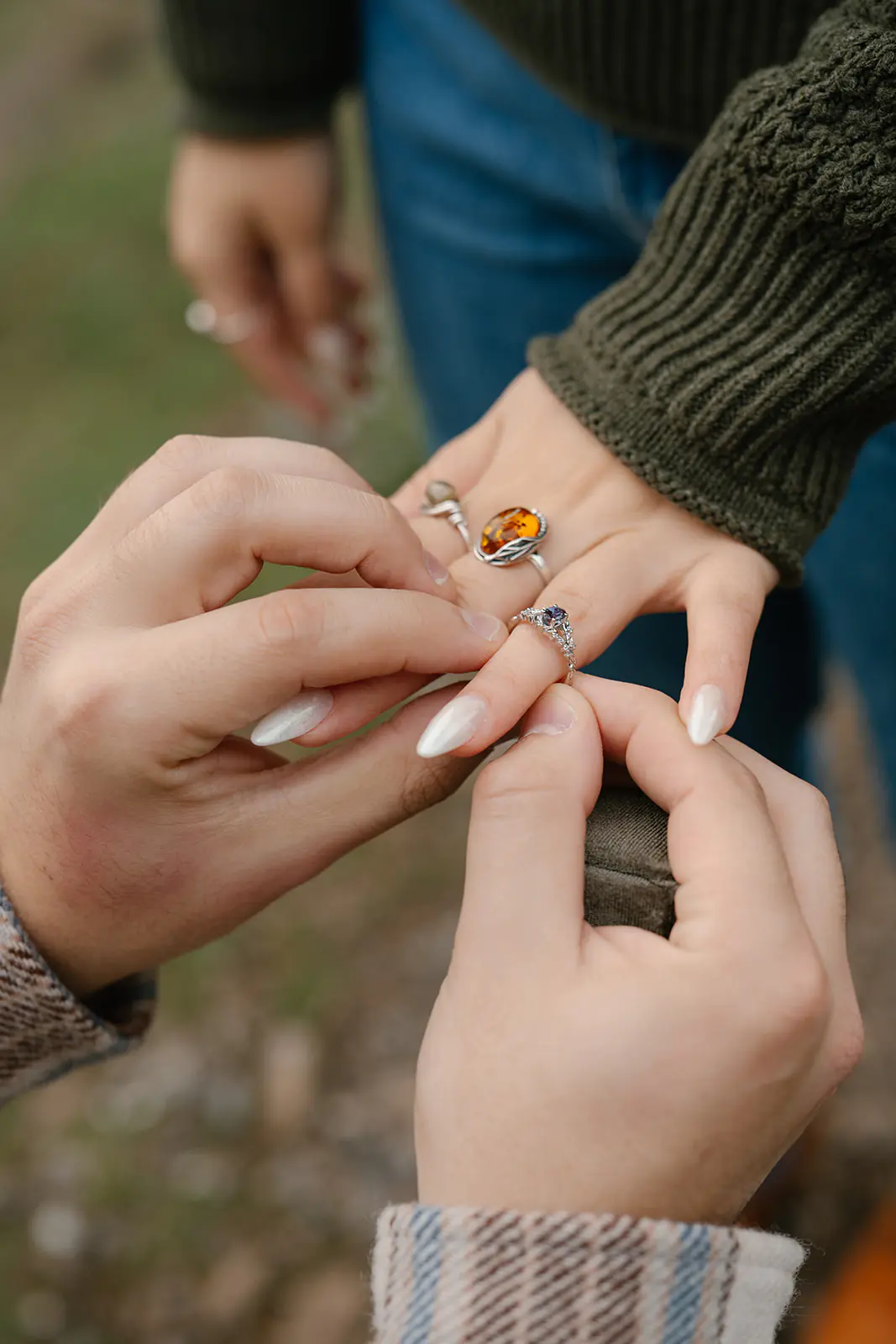 Jonathan gently slides the engagement ring onto Ashley’s finger.