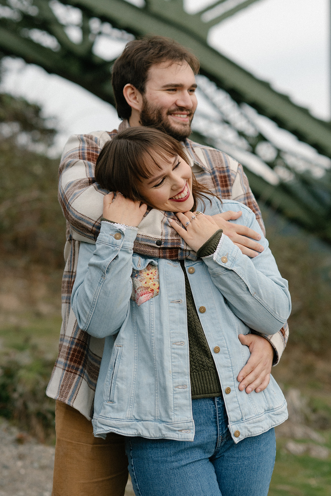 Ashley laughs while Jonathan wraps his arms around her during their engagement session at Deception Pass.