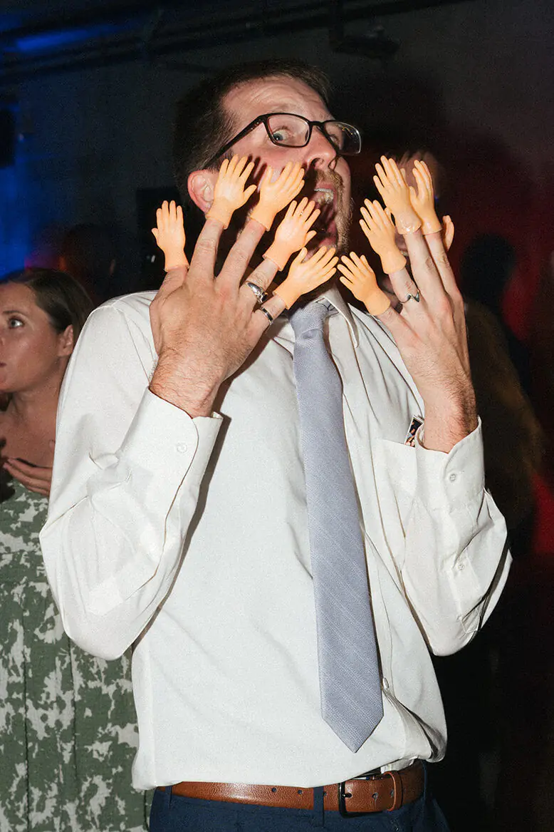 Wedding guest wearing tiny plastic hands on his fingers during the Fremont Foundry reception