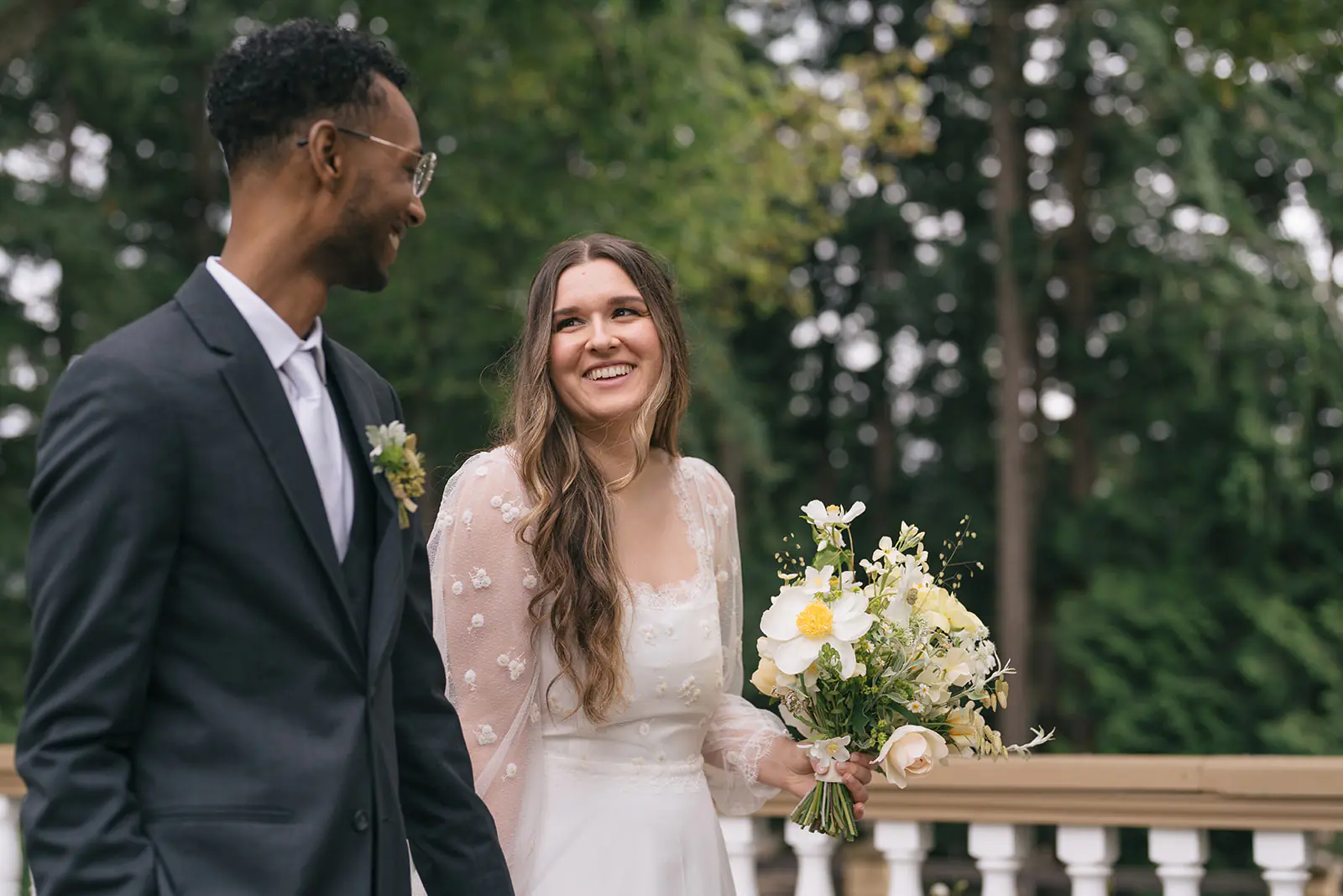 Bride and groom smiling at each other while walking along the terrace at Lairmont Manor.