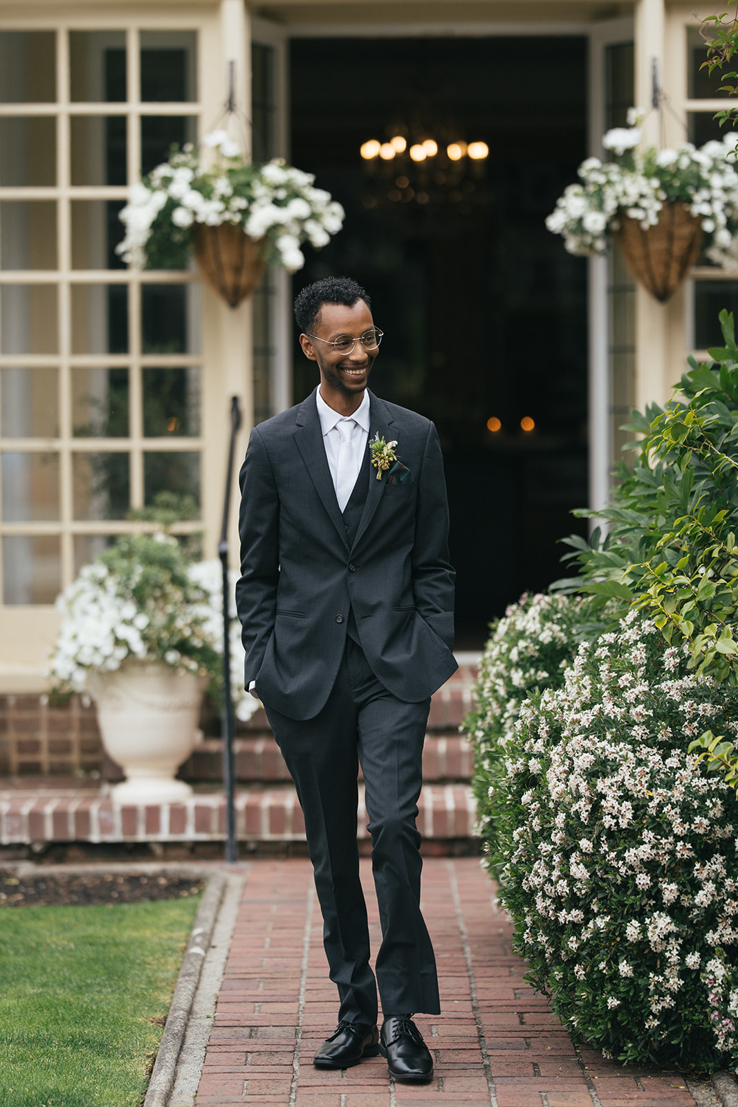 Groom walking along brick pathway toward outdoor ceremony at Lairmont Manor