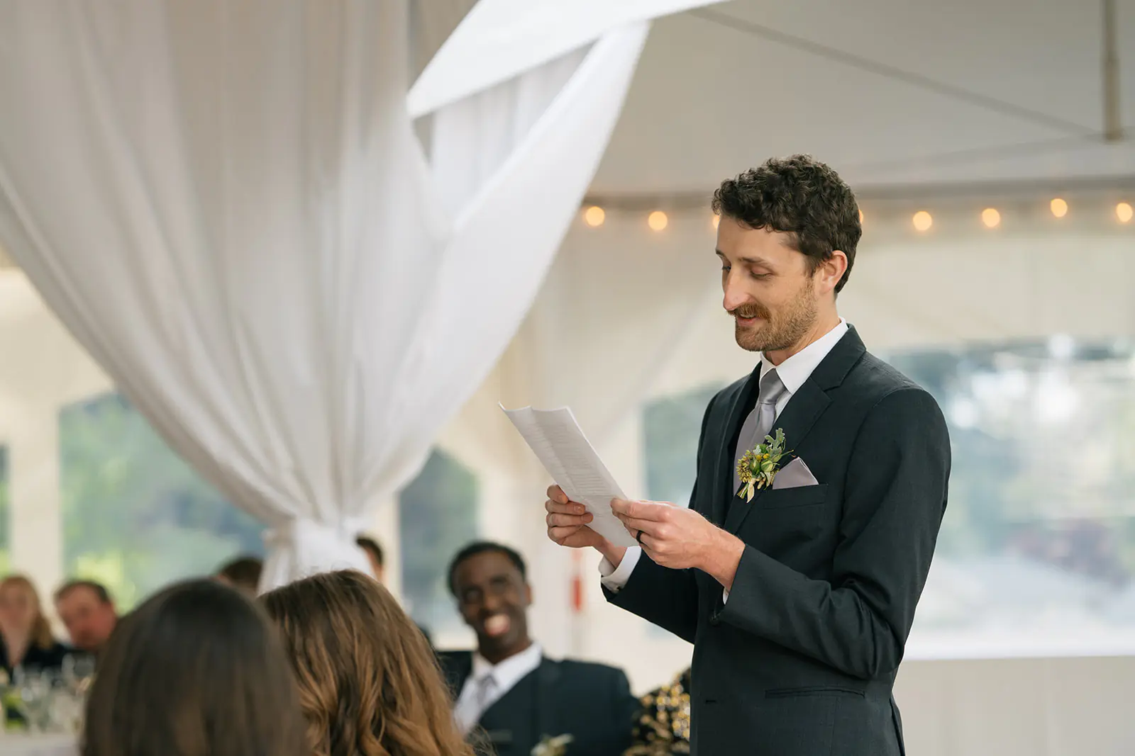 Best man giving a wedding speech inside the reception tent at Lairmont Manor