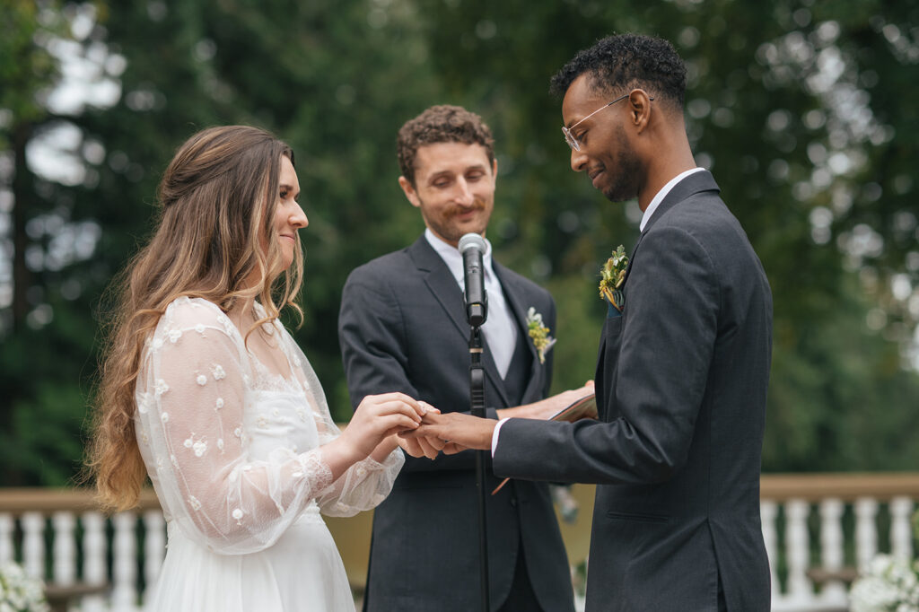 Bride placing ring on groom’s finger during wedding ceremony