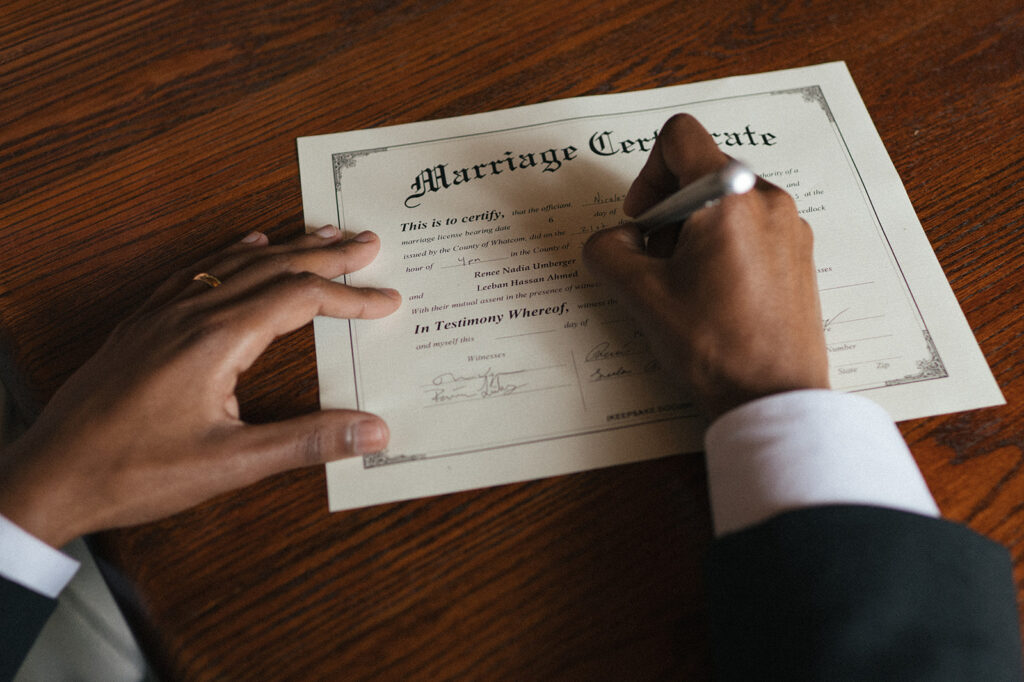 Close-up of groom signing marriage certificate