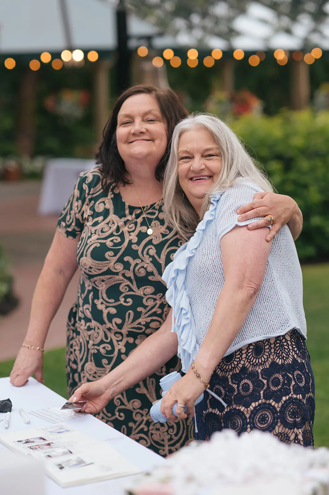 Two guests smiling while signing the guest book at an outdoor Lairmont Manor wedding