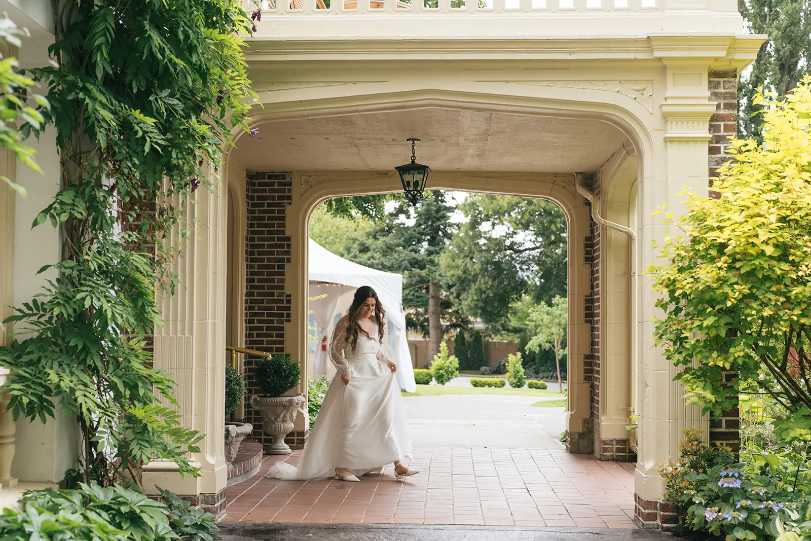 Bride walks beneath ivy-covered archway at Lairmont Manor moments before the first look.