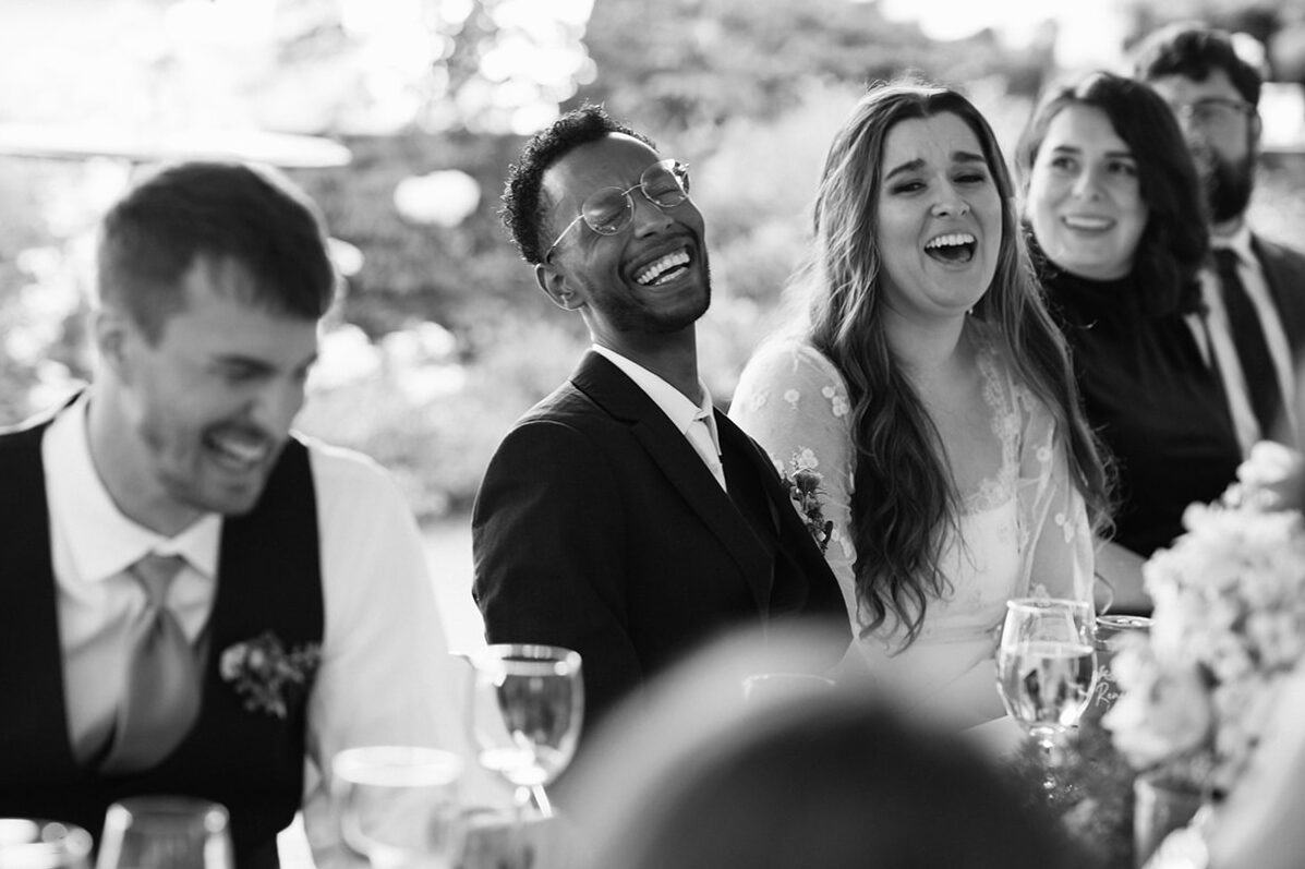 Black and white photo of wedding guests laughing during speeches at Lairmont Manor reception