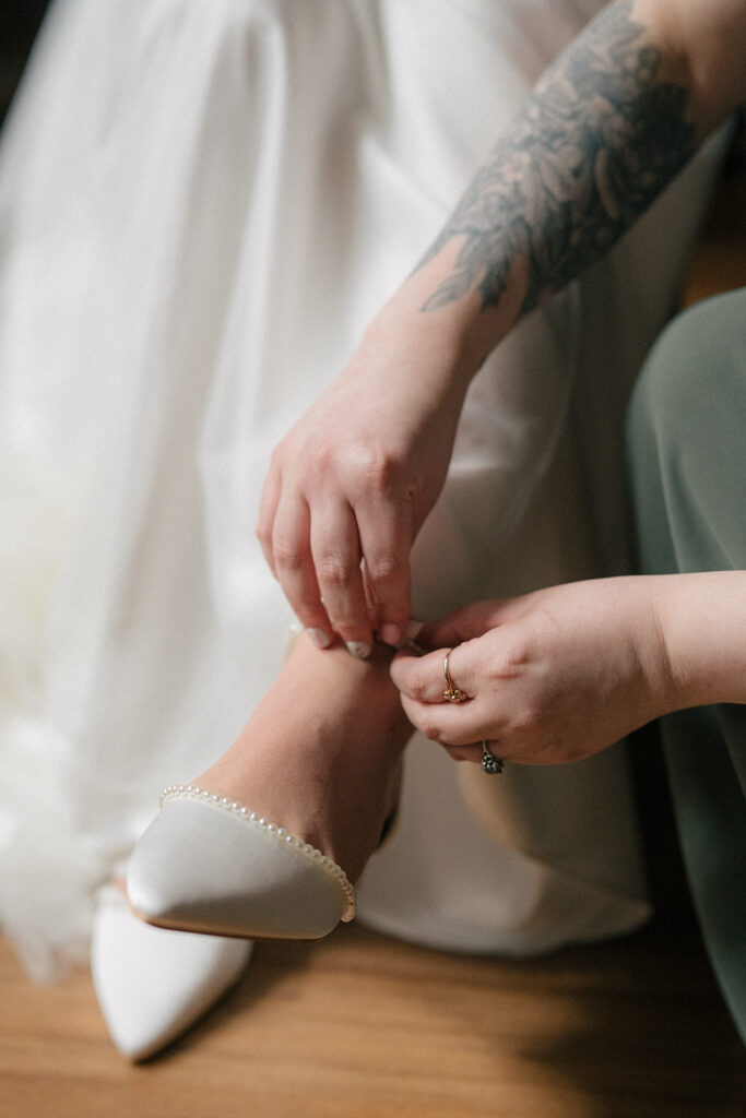 Bridal shoe being fastened during wedding morning preparations