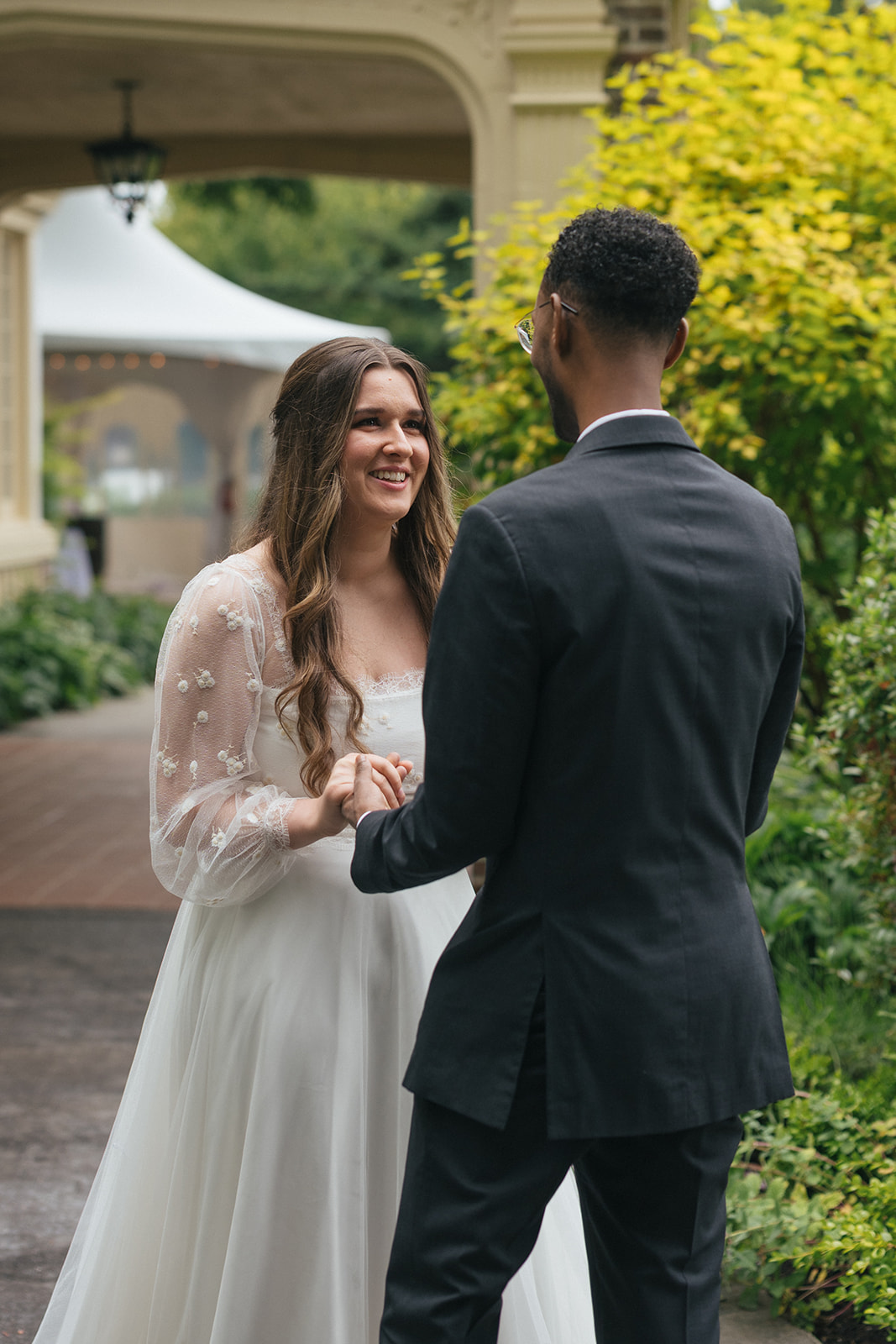 Bride and groom hold hands and smile during their private first look at Lairmont Manor.