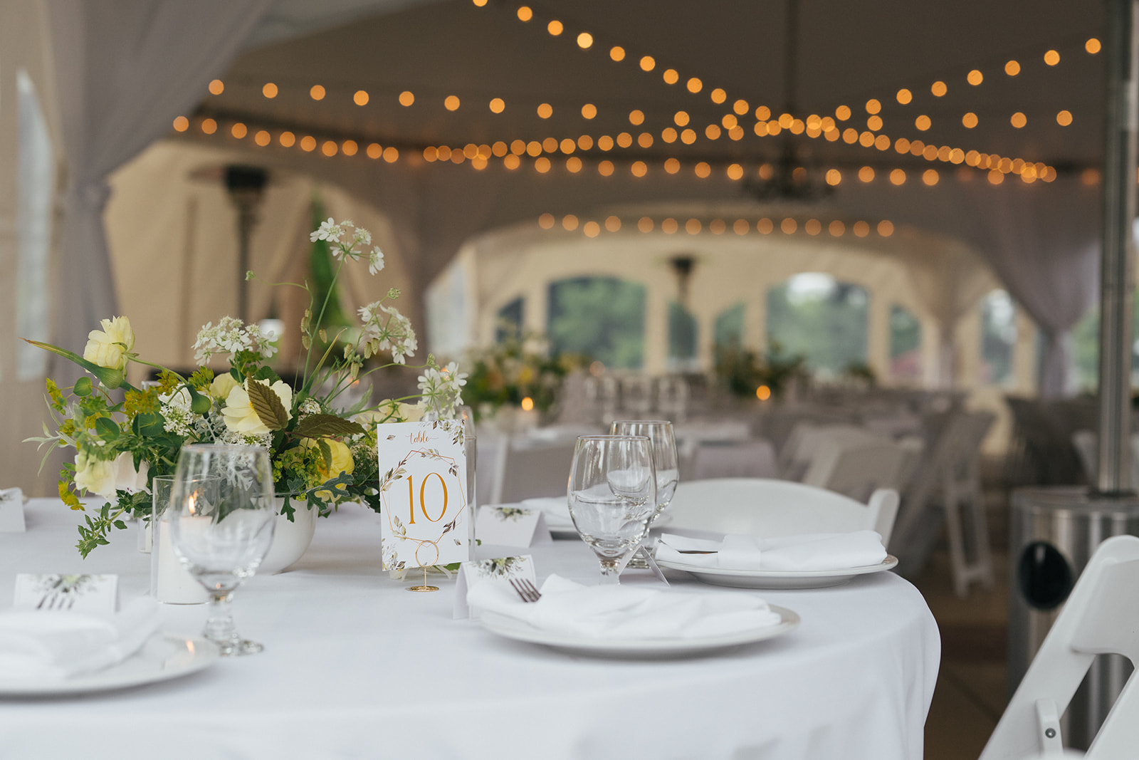 Reception table with table number ten, fine place settings, and soft floral arrangement