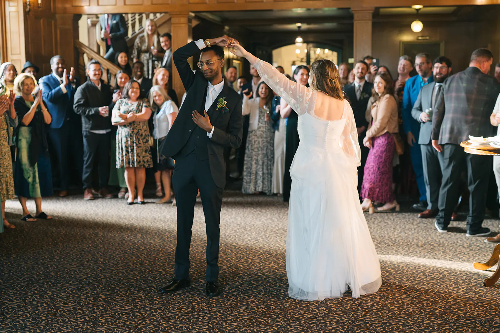 Groom twirling the bride beneath his arm during their first dance at Lairmont Manor