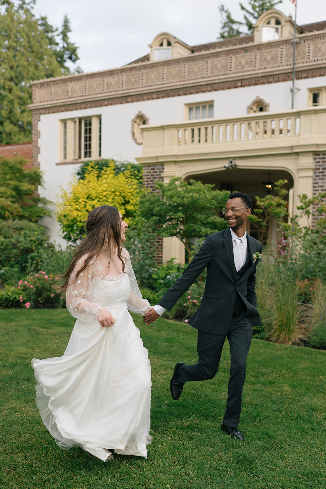 Bride and groom running hand in hand across the lawn at Lairmont Manor.