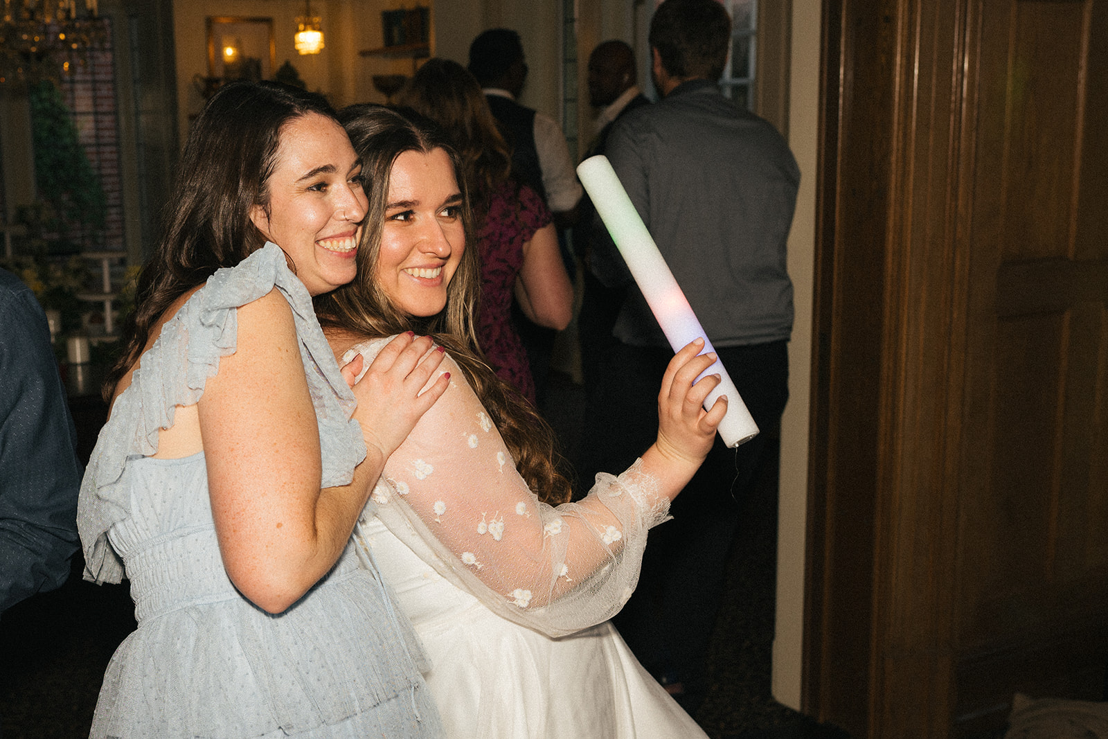 Bride hugging a guest while holding a glow stick on the dance floor at Lairmont Manor
