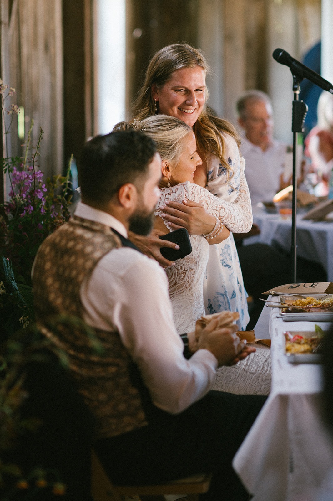 The bride's sister embraces her as guests around them applaud