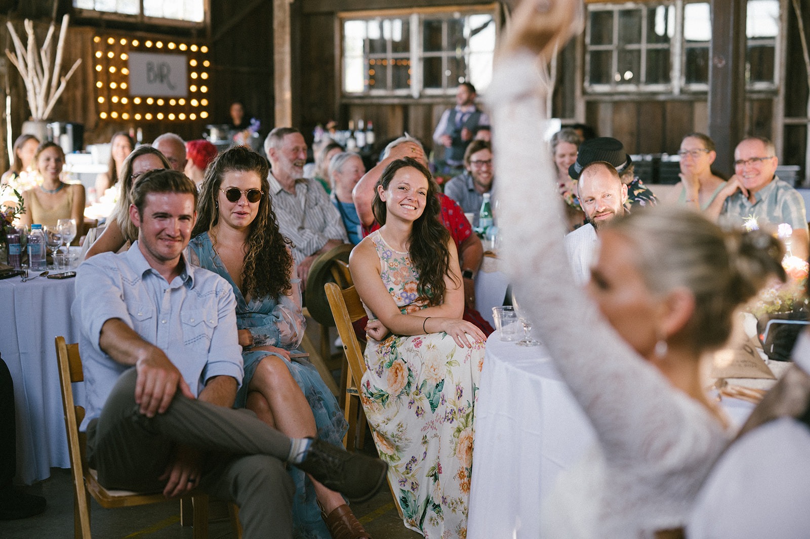 Guests laugh and look on as the bride and groom play the shoe game during their wedding reception