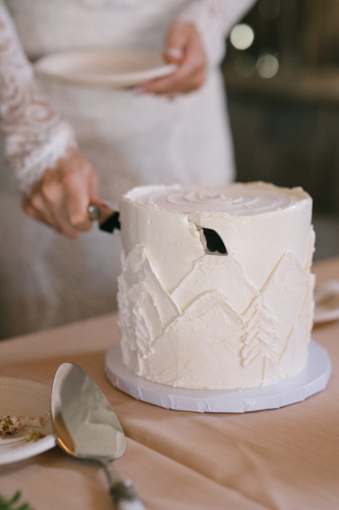 A slice is cut from the cake at this Saltbox Barn wedding reception