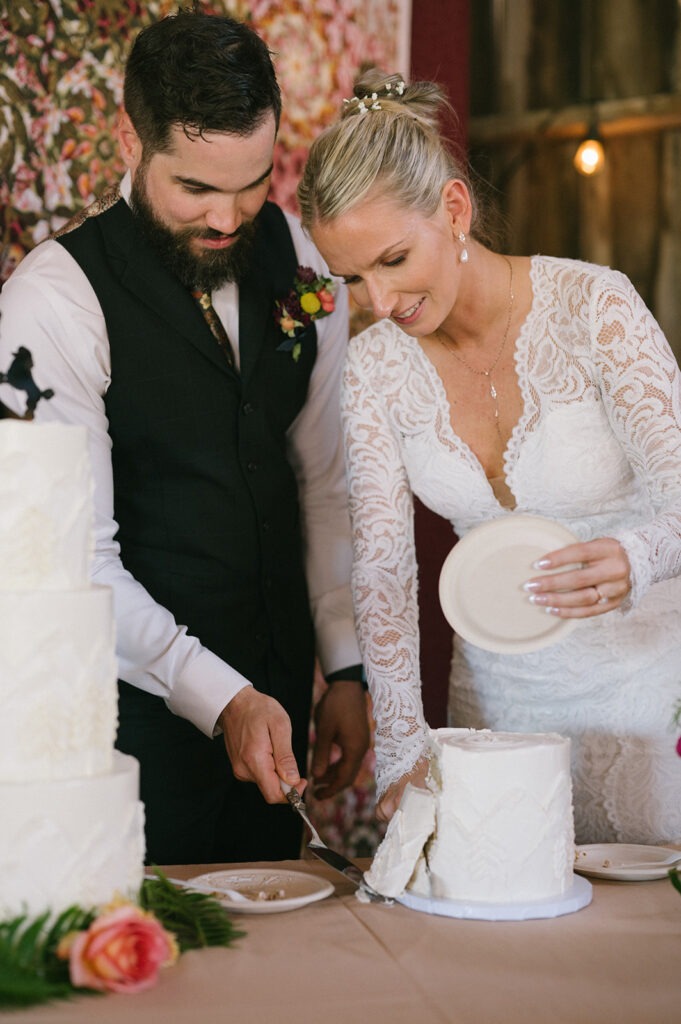 Groom and bride cut into their wedding cake together during the reception