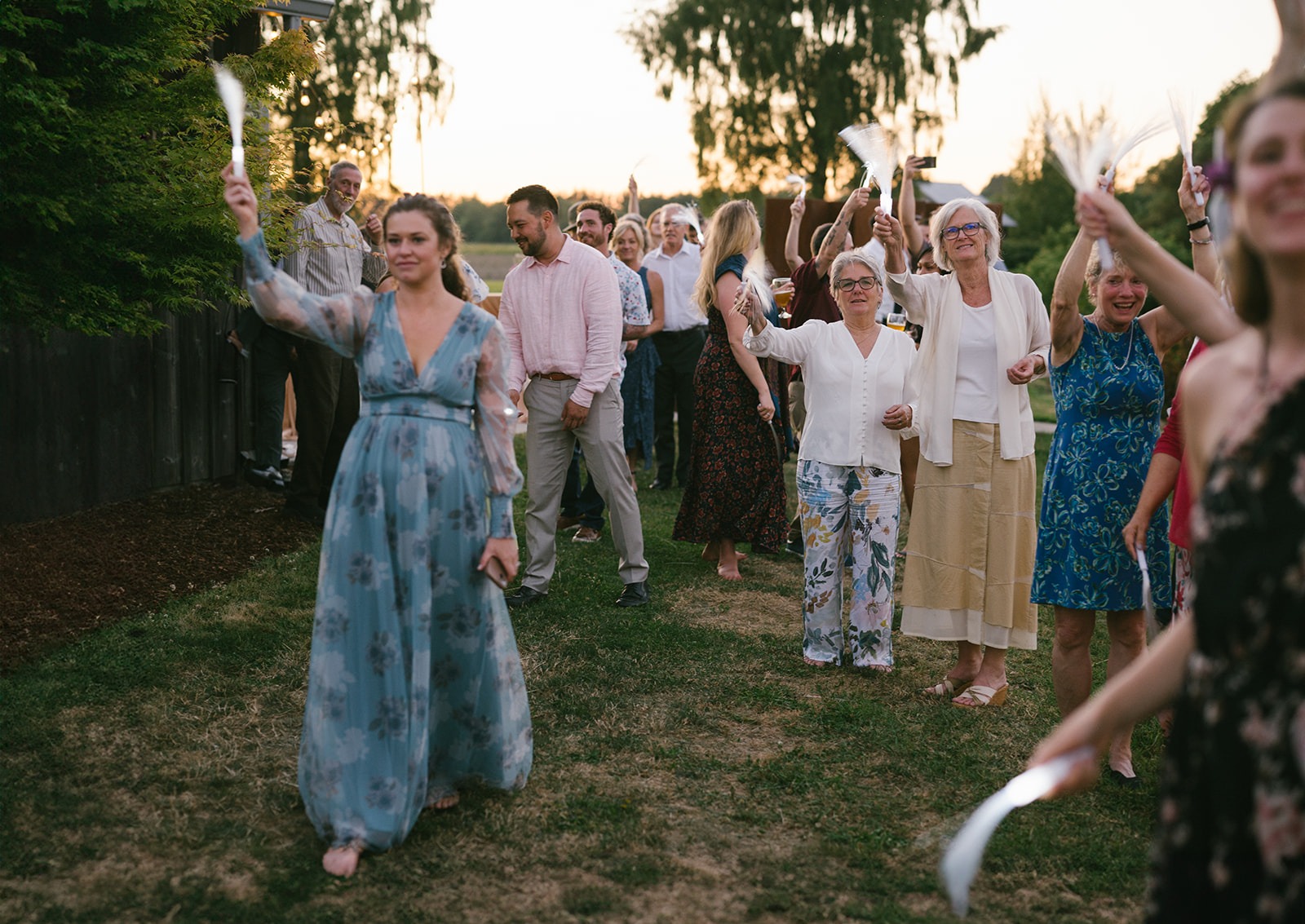 A guest in a blue dress walks through a tunnel of raised ribbon wands