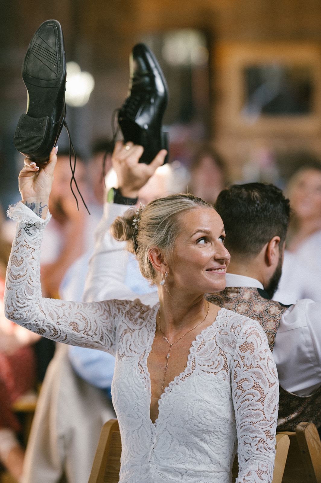 Bride laughs and raises her shoe overhead during the reception tradition
