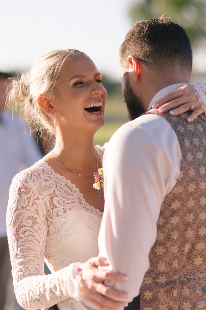 Bride laughs joyfully while embracing the groom at their Saltbox Barn wedding during the first dance