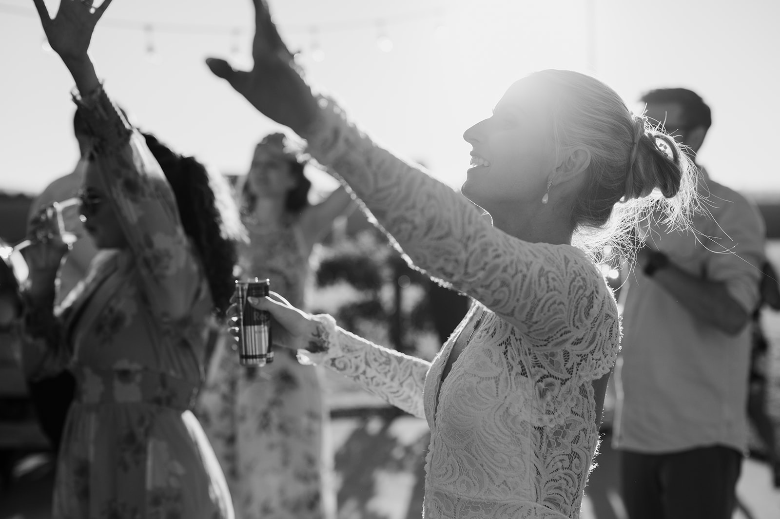 A black-and-white shot captures the bride dancing with her arms raised