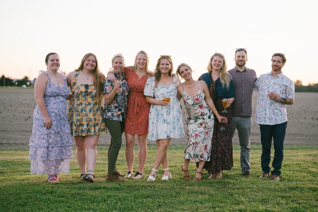A group of nine friends pose together on the lawn during golden hour