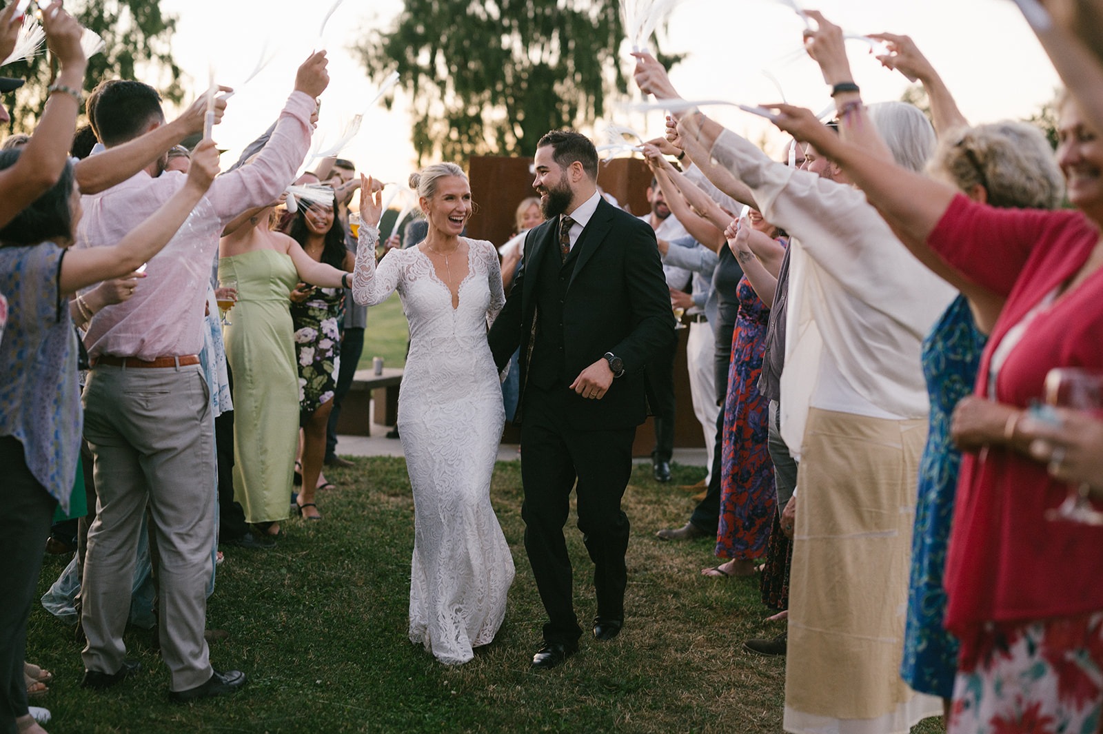 Newlyweds walk through cheering guests after their Saltbox Barn wedding ceremony