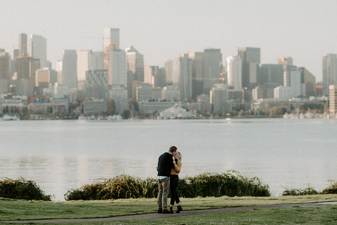 Couple embracing with the Seattle skyline reflected across Lake Union