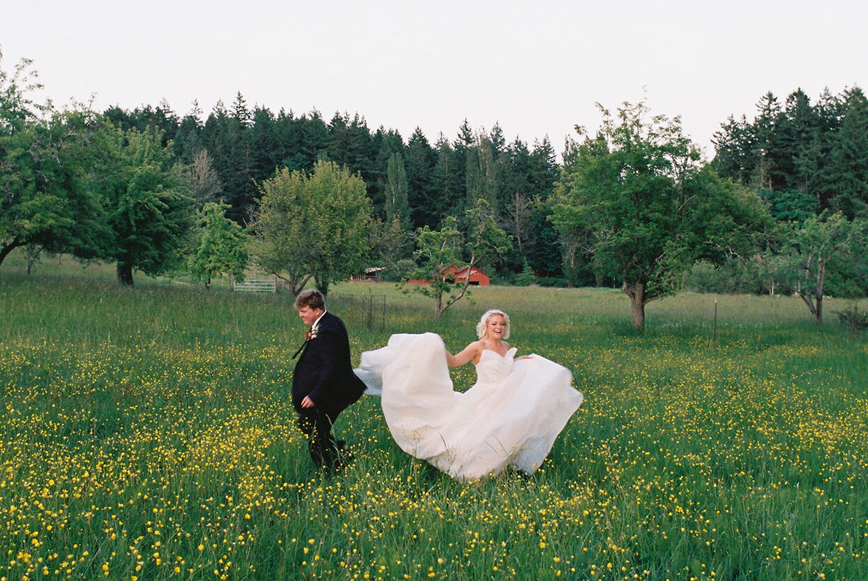 Newlyweds running through a wildflower field at sunset