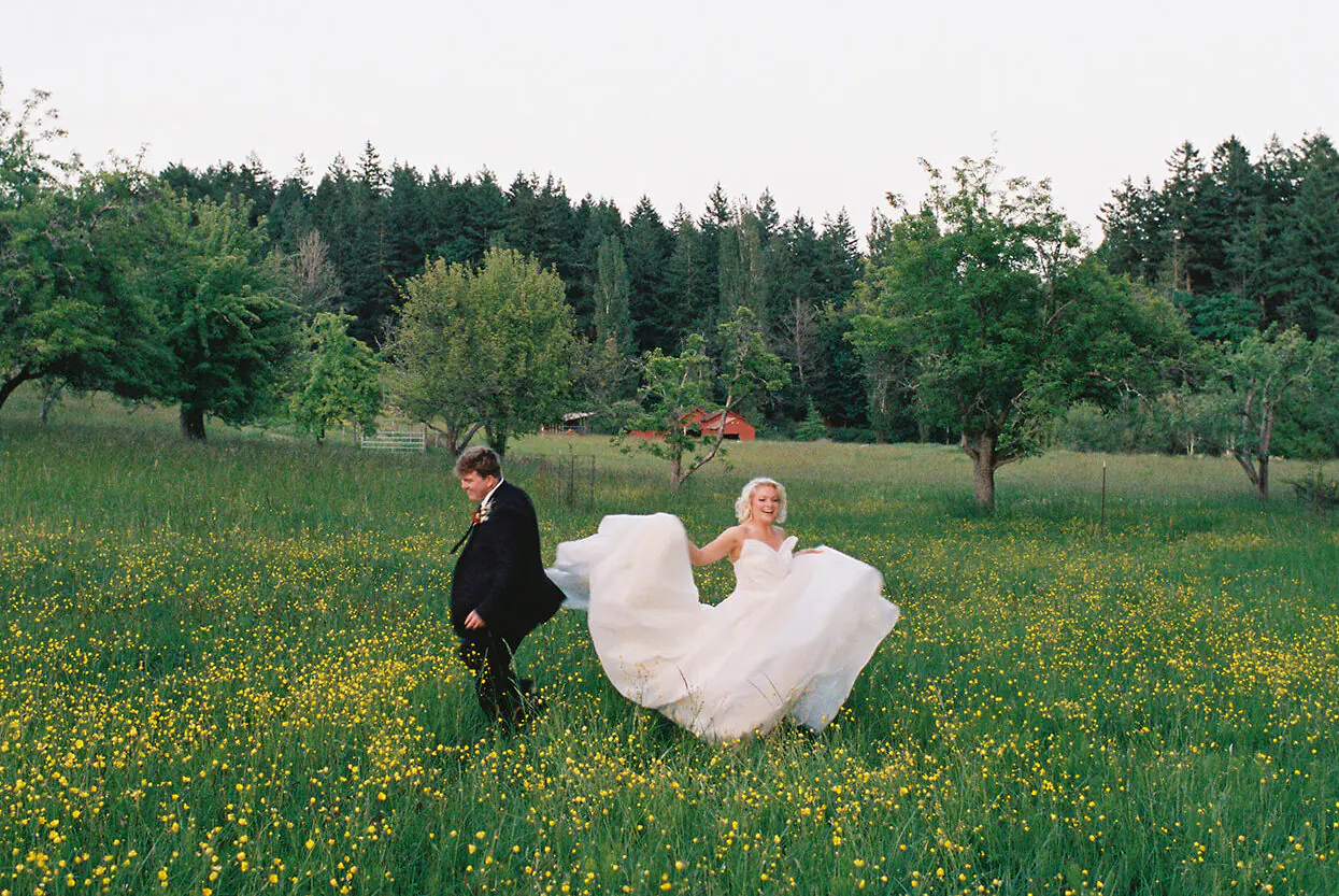 Newlyweds running through a wildflower field at sunset