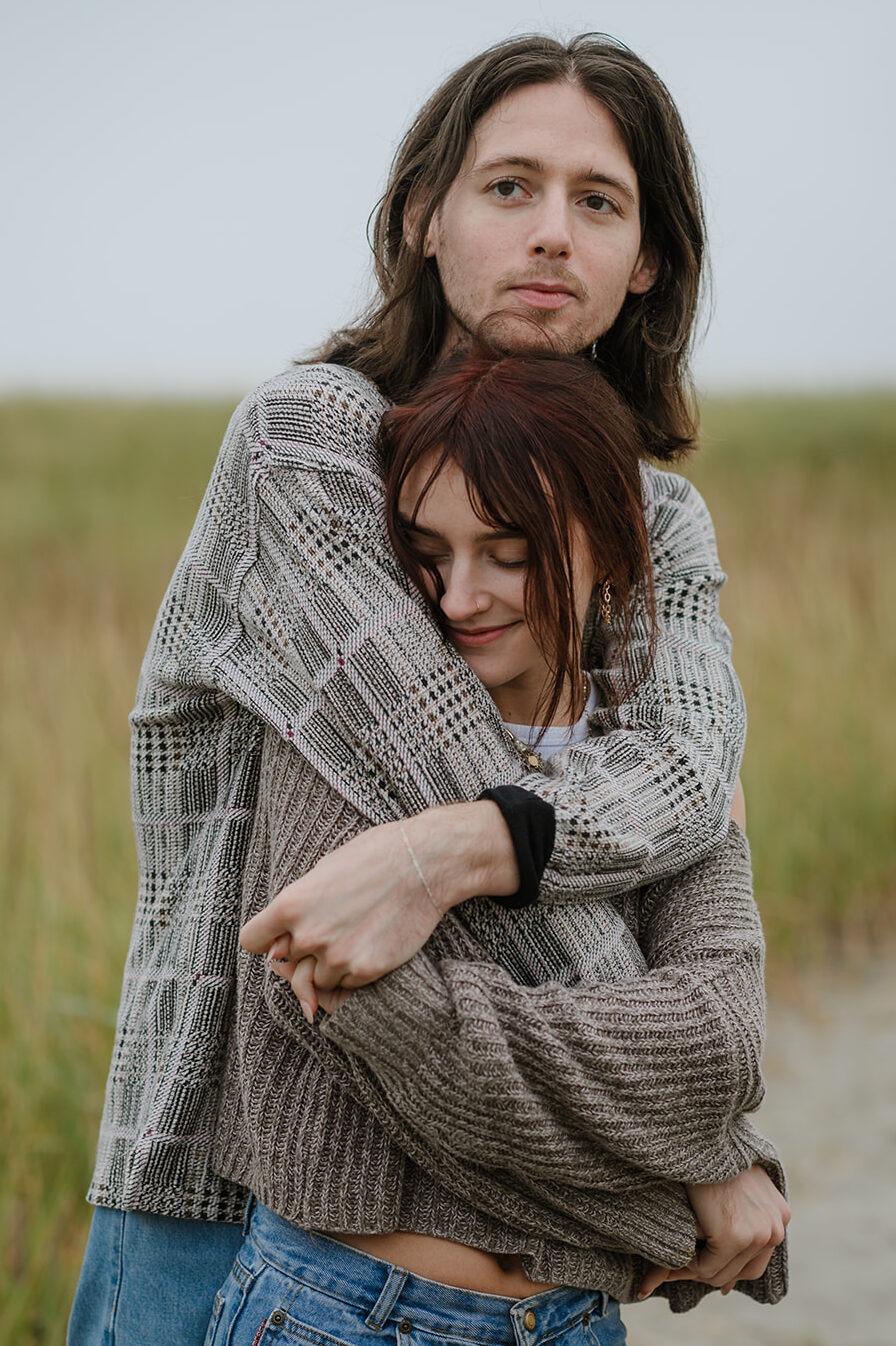 Content couple in a close hold amidst the grassy dunes of the Oregon coast