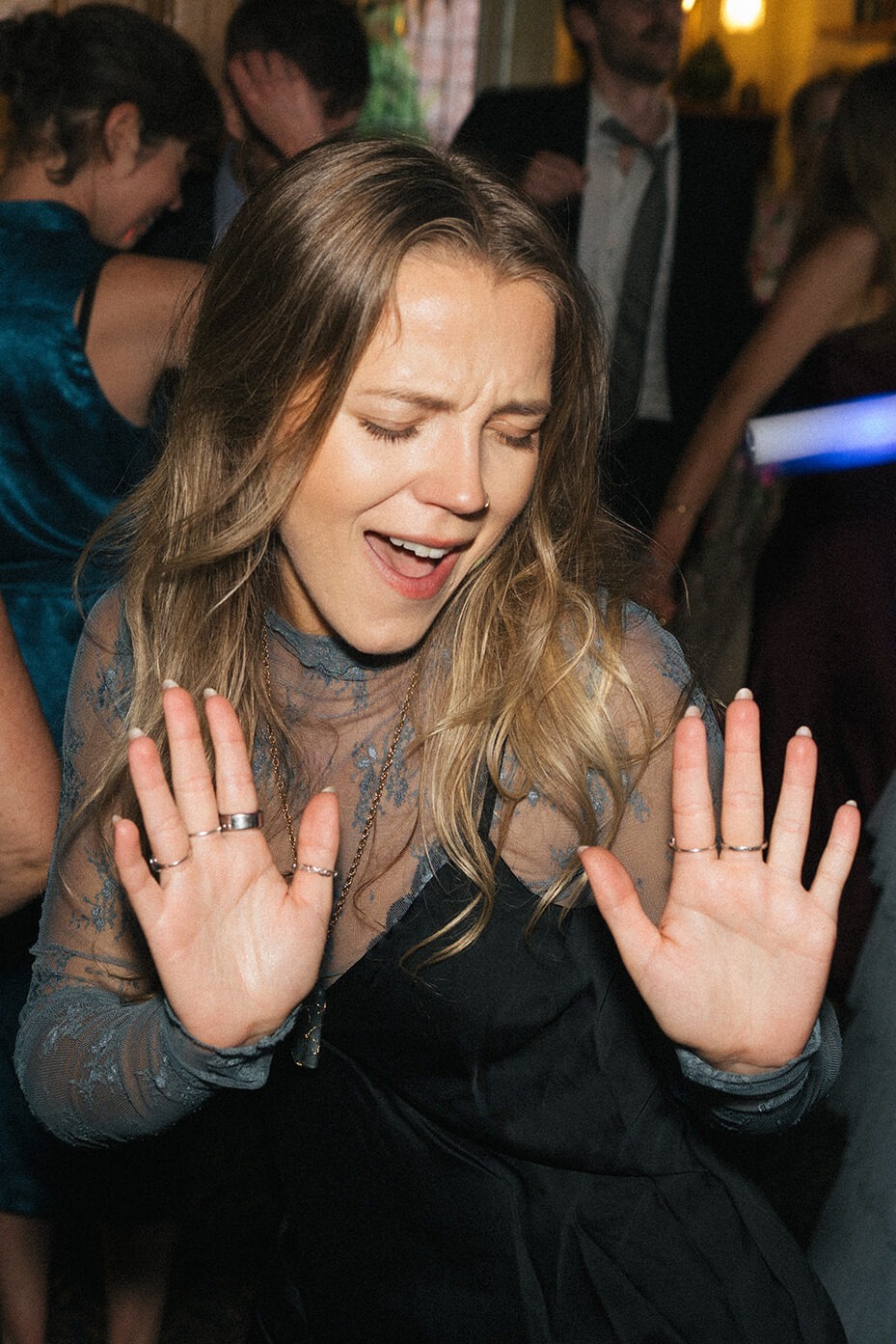 Wedding guest dancing with her hands raised on the crowded ballroom dance floor at Lairmont Manor