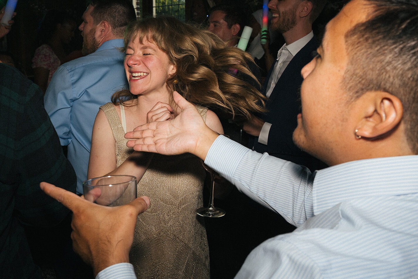 Wedding guests spinning and dancing together under colorful reception lighting at Lairmont Manor