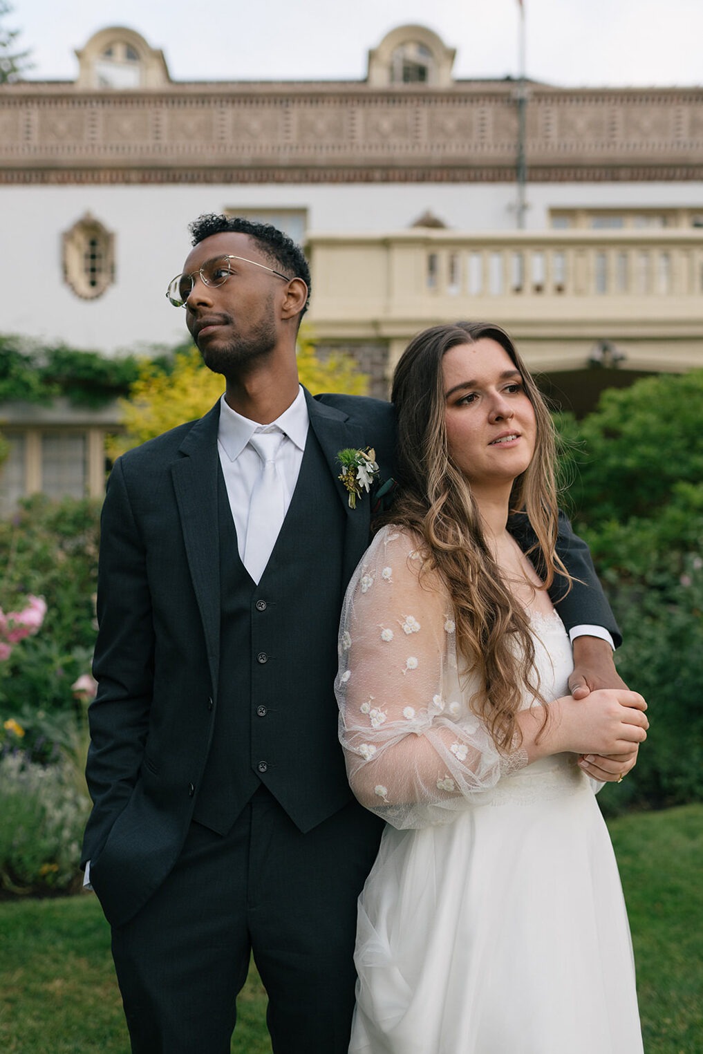 Bride and groom embracing in front of Lairmont Manor with historic architecture in the background.