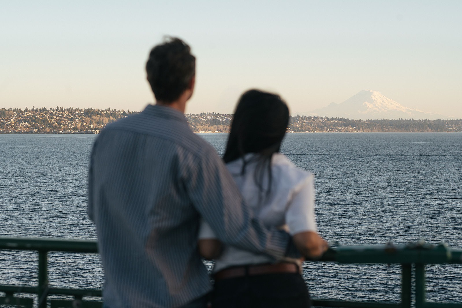 Couple looking out across the water toward Mount Rainier during a Washington State Ferry engagement session