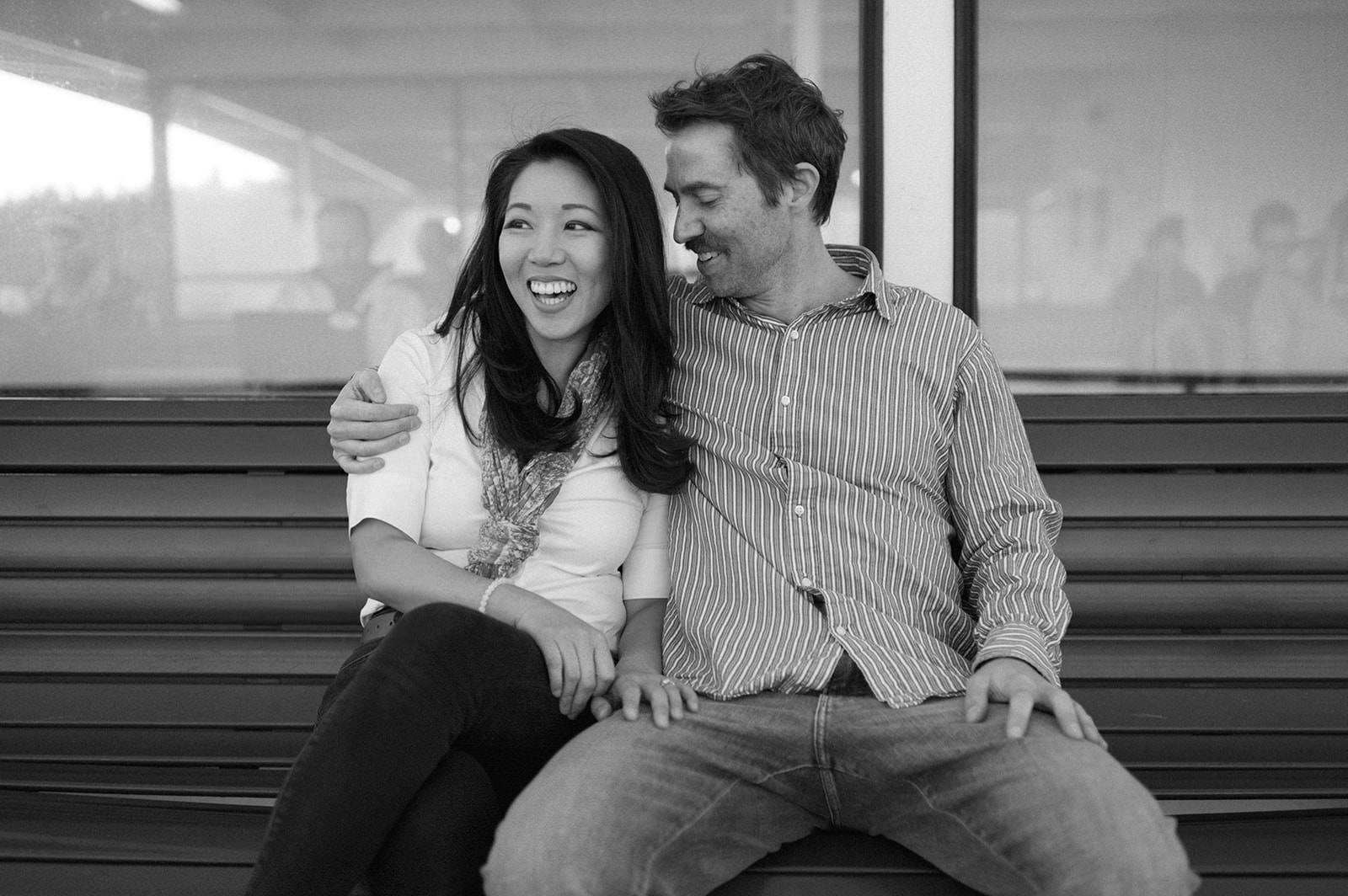 Black and white photo of a couple sitting close together on a ferry bench during a Washington State engagement session
