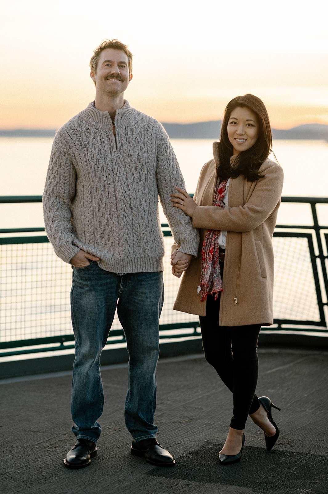 Couple standing together on the ferry deck at sunset during a Washington engagement session