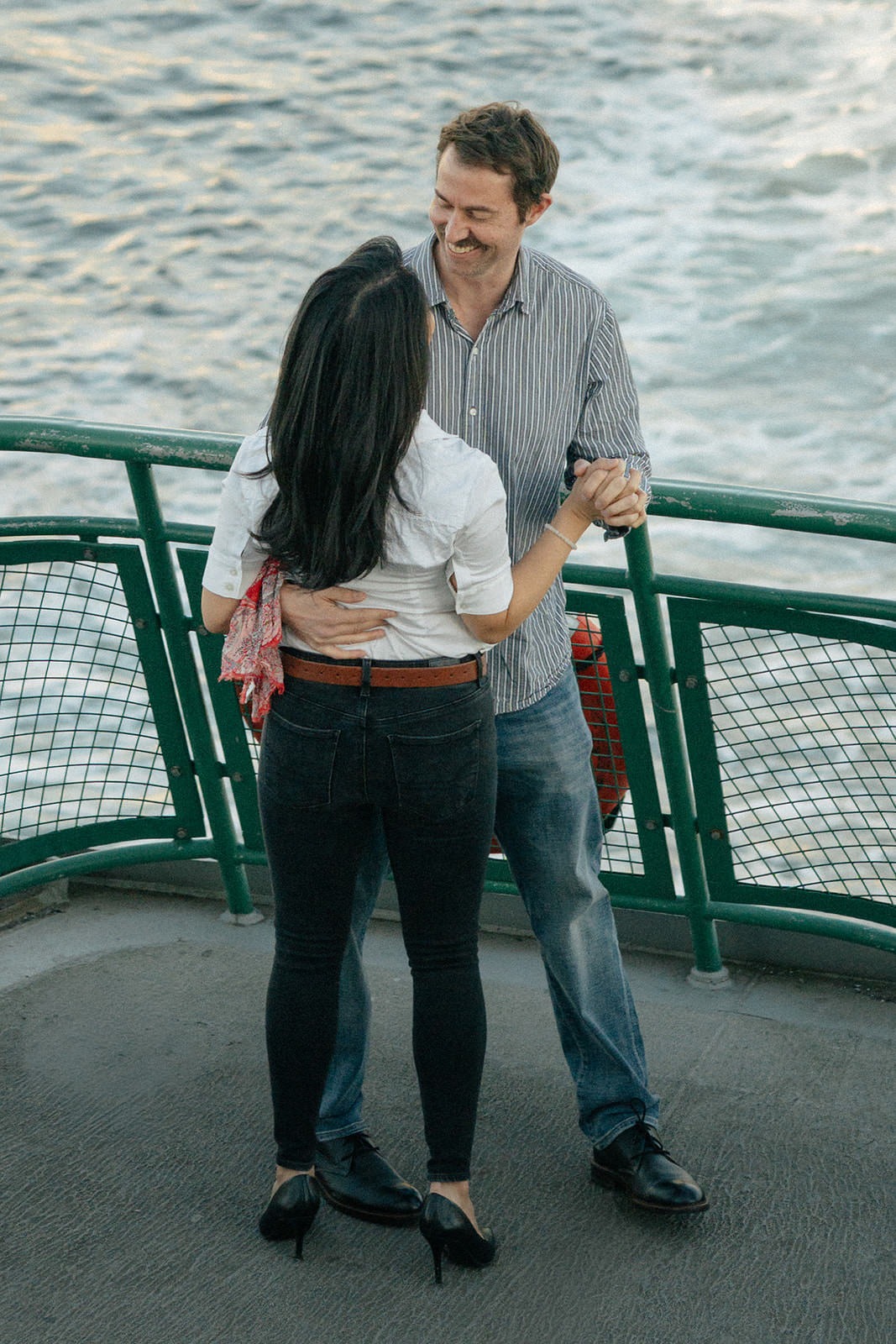 Couple smiling and dancing together on the ferry deck during a Seattle engagement session