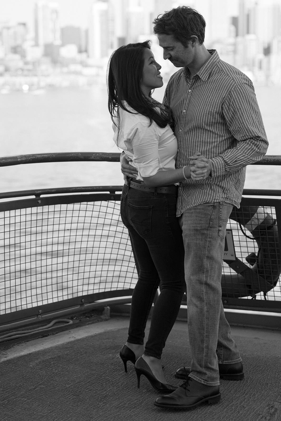 Black and white engagement photo of a couple embracing on the Washington State Ferry
