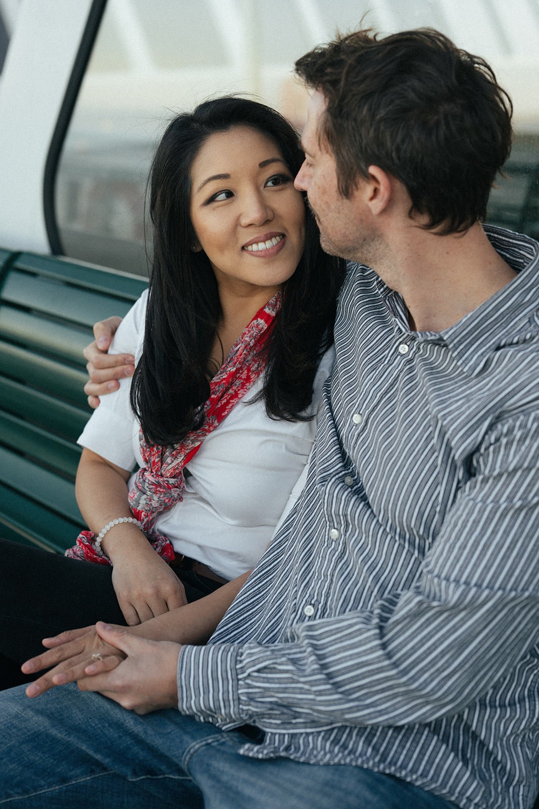 Couple sitting close together on a ferry bench and looking at each other during an engagement session