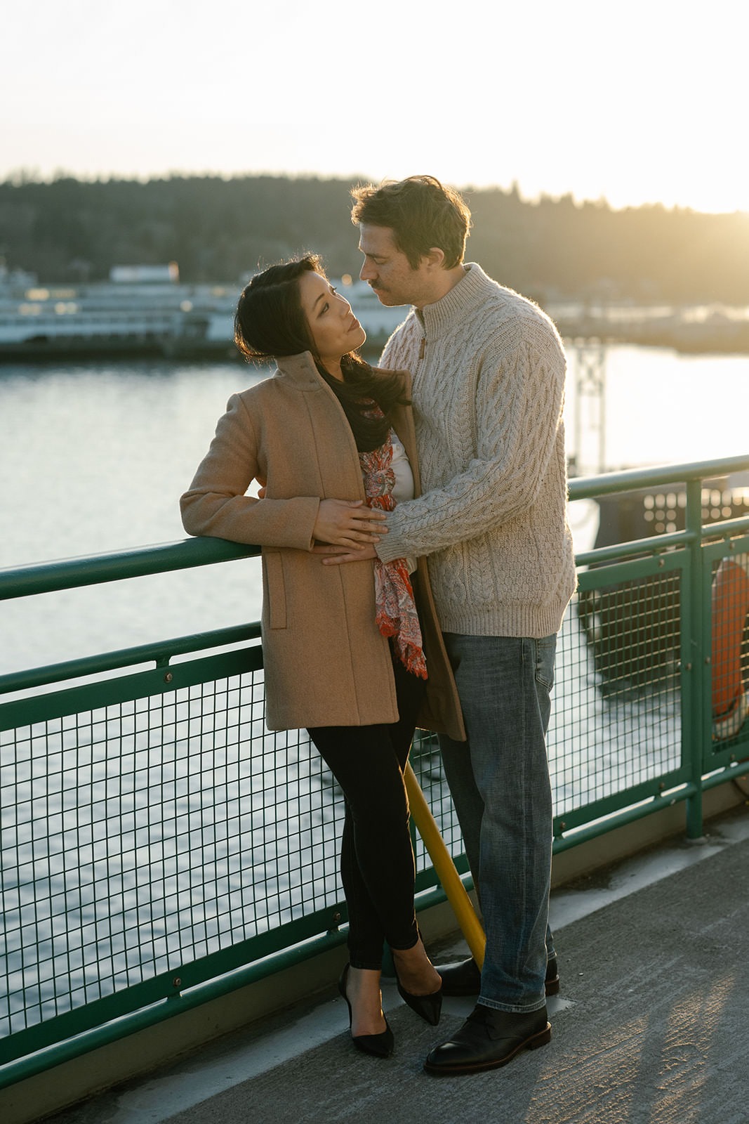 Couple embracing by the ferry railing at sunset during a Washington State engagement session