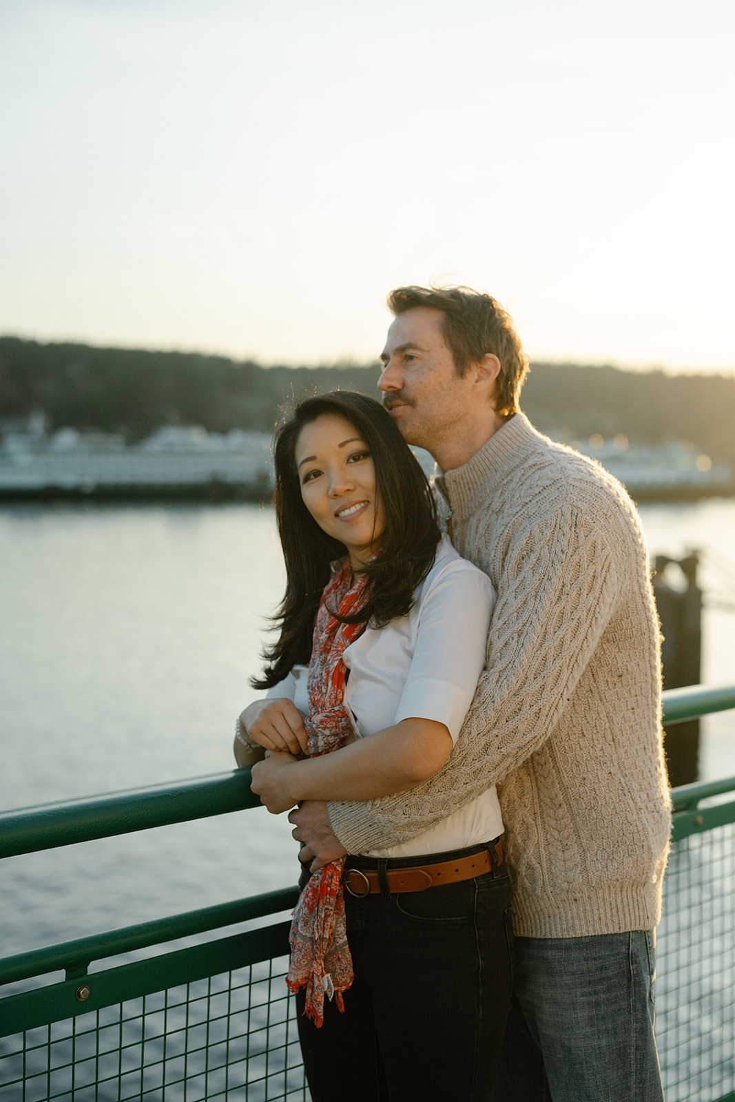 Couple smiling together by the ferry railing during a sunset engagement session