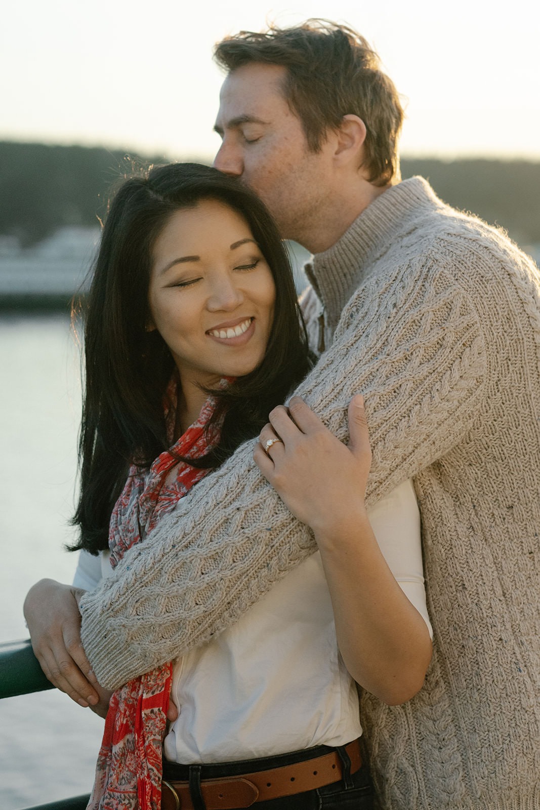 Couple hugging on the ferry deck with soft golden light during a Seattle engagement session