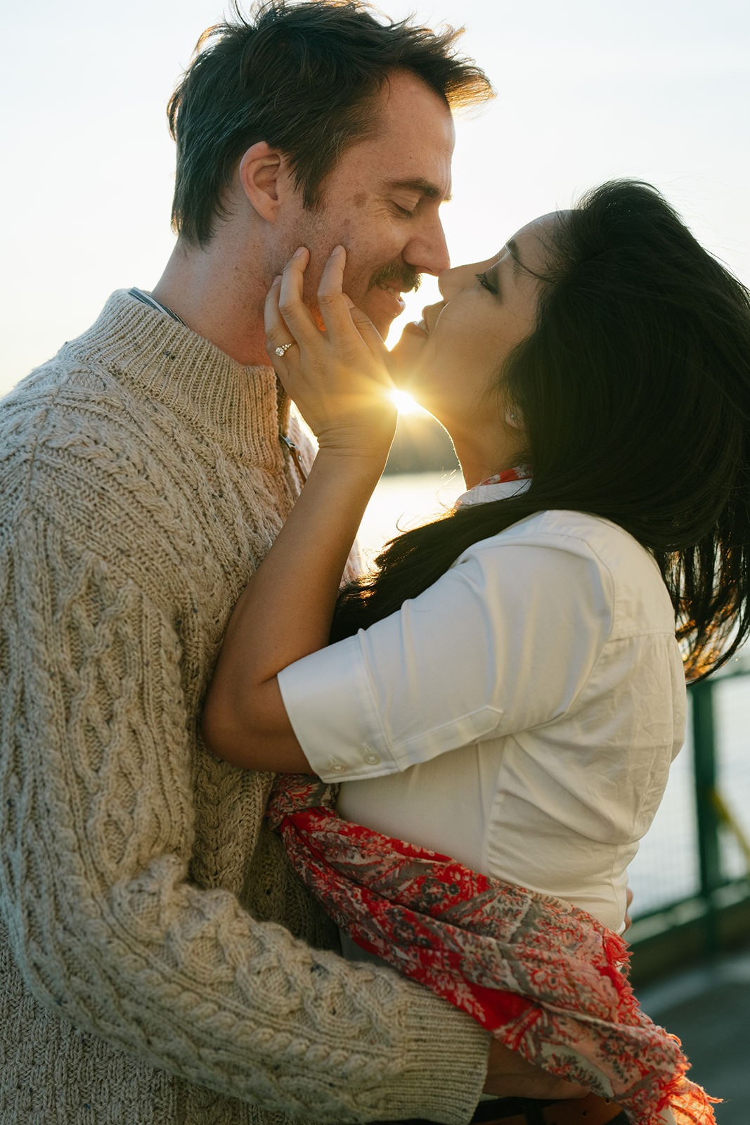 Close up of a couple embracing with sun flare during a Washington State Ferry engagement session